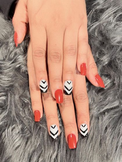 A bold geometric design combining red polish with black and white chevron patterns for a high-contrast, graphic look.
