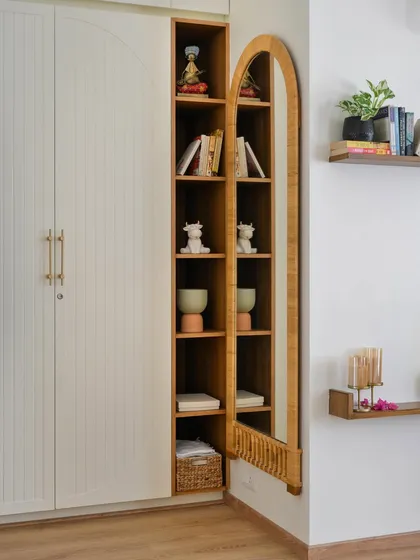 A simple PU-polished wardrobe is elevated with an arched, bamboo-framed mirror and an integrated open shelving unit, adding natural warmth and display space.