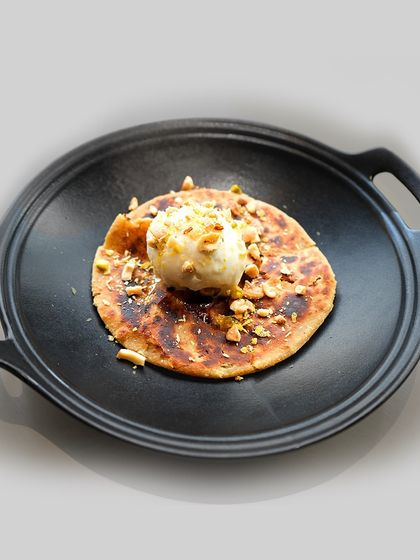 A full view of the Mawa Mishri Parantha dessert, served on a traditional cast-iron plate. It’s a warm, comforting, and surprising end to a meal.
