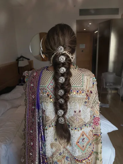 A stunning, intricate bubble braid adorned with large, sparkling accessories. This is a true statement hairstyle for a bride who wants something unique for her Mehendi or Sangeet.