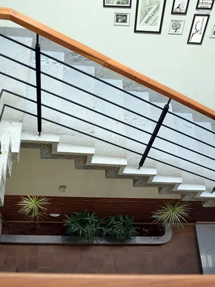 Looking down into the central atrium, a core feature of this tropical modern home. The staircase wraps around this lightwell, which houses indoor plants and brings nature inside.