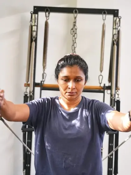 Focus and determination define this client's form as she performs a chest press on the Cadillac. This exercise builds upper body strength and stability, toning the arms and shoulders.