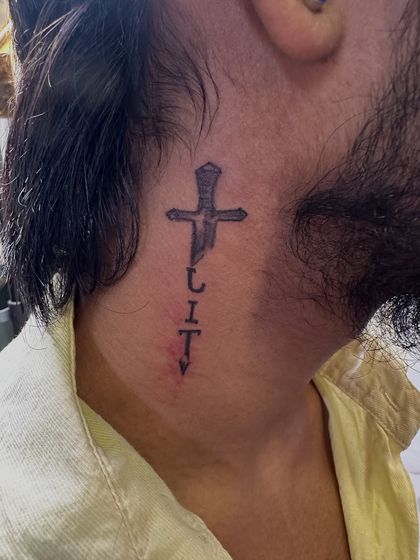 A unique and edgy neck tattoo of a cross that transforms into a dagger with the word 'CULT'. This is a bold, fine-line statement piece.