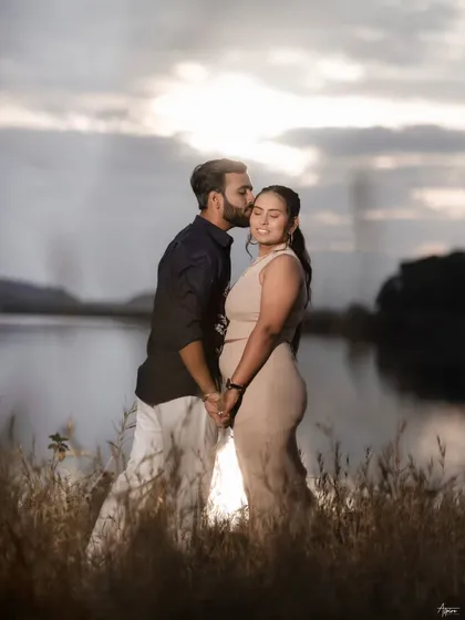 A romantic silhouette-style shot of Prem and Jinal against the setting sun. The warm light and the tender kiss on the forehead create a timeless and emotional image by the lake.
