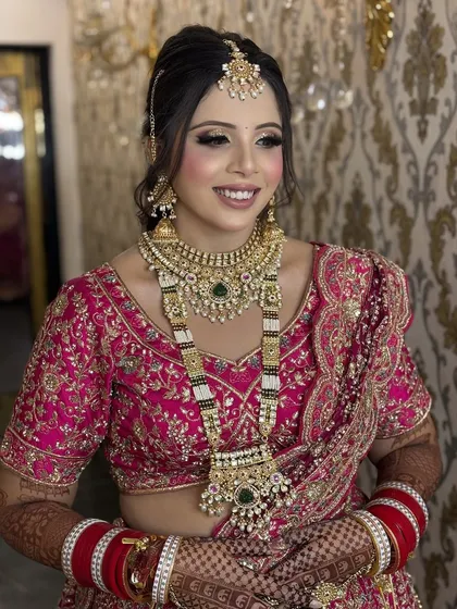A smiling bride ready for her big day. This regal look in a pink lehenga features soft smokey eyes, a radiant base, and perfectly coordinated jewellery, showcasing a complete and cohesive bridal style.