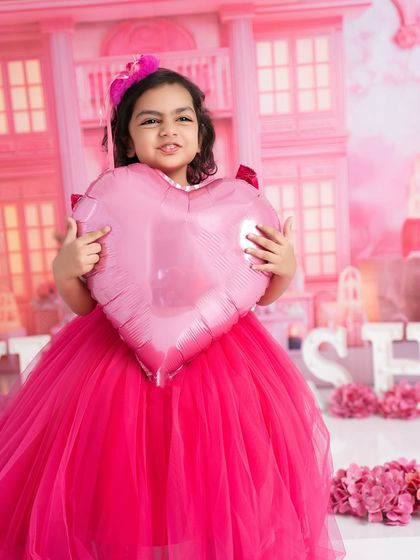 A real-life Barbie doll in a world of pink. This older girl is holding a heart balloon in a beautiful, custom-made Barbie dreamhouse set.