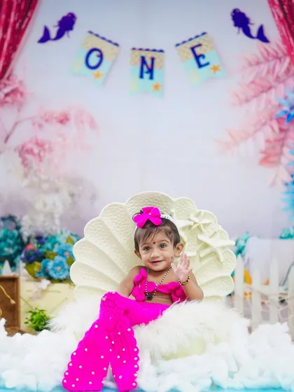 A sweet smile and a wave make this little mermaid's first birthday portrait absolutely unforgettable.