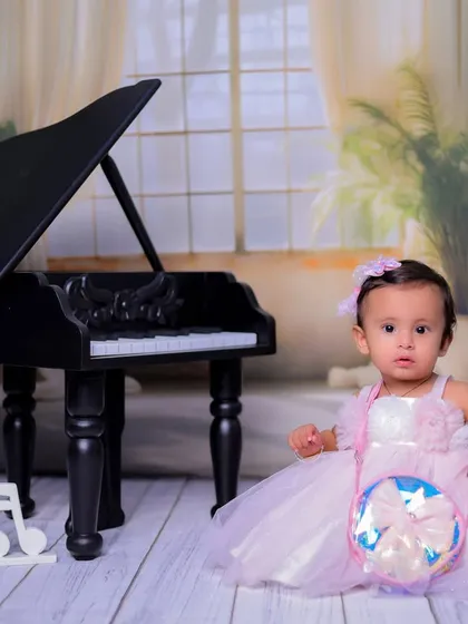 Sitting gracefully by the piano, this little girl is the star of the show. This photo showcases another lovely pose from our 'Mini Musician' series.