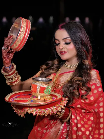 A serene shot with the model looking down at the lit diya on her thali.