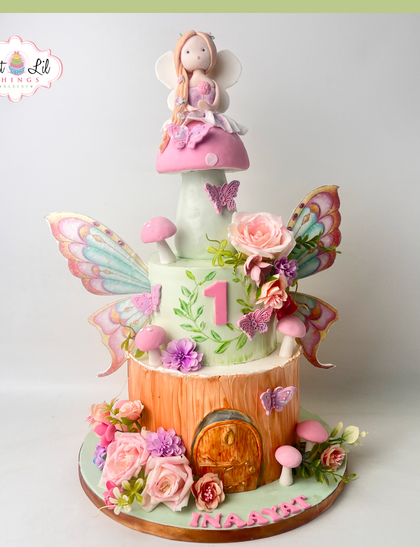 A magical fairytale comes to life in this enchanting fairy-themed cake. The multi-tiered design features a tree-trunk base, fairy wings, and whimsical mushrooms.