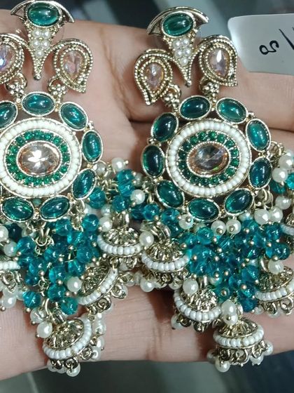 A pair of heavy chandelier earrings with blue-green beads, jhumkis, and intricate stone work.