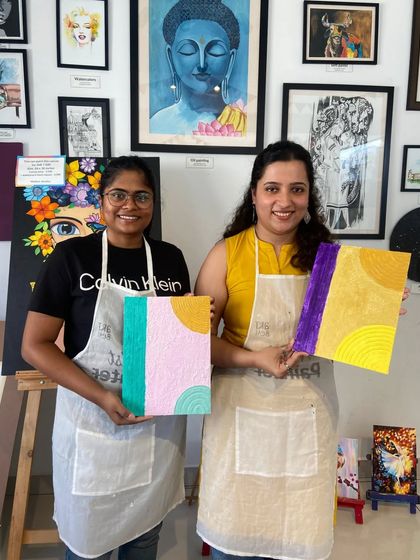 Two friends showing off their finished texture paintings. It's a fun and tactile experience, perfect for a creative day out.