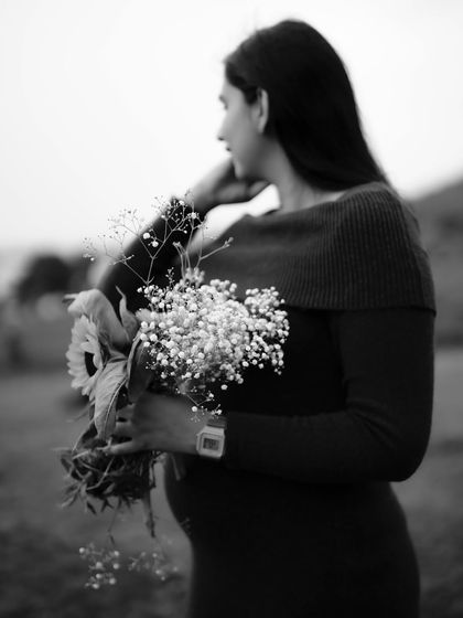 A black and white close-up of the mom-to-be holding a bouquet of flowers. The focus is on her peaceful expression and the delicate textures of the flowers.