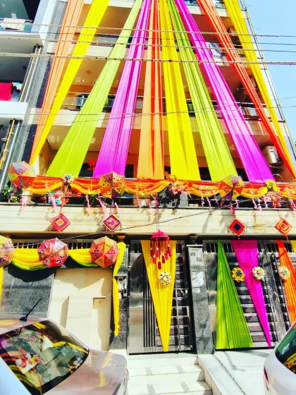 A full view of a house decorated for a wedding, with vibrant drapes, umbrellas, and traditional hangings creating a festive spectacle.