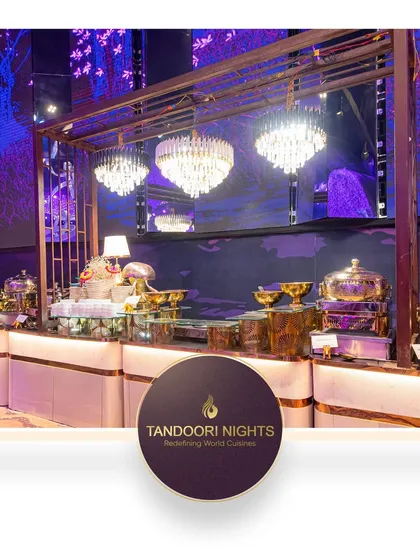 We elevate your event with stunning food presentations that captivate and delight. This image shows a luxurious buffet setup under glittering chandeliers.