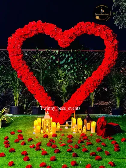 A romantic outdoor setup perfect for a proposal. We created a large heart-shaped arch with red flowers and filled the ground with scattered rose petals and battery-operated candles for a magical effect.