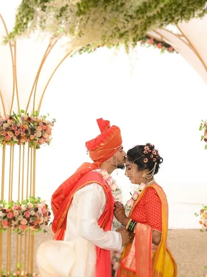 A close up of the groom's tender forehead kiss under the stunningly decorated mandap, with the ocean in the background.