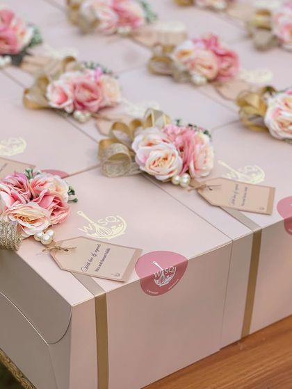 A detailed look at the handcrafted toppers on our return favour boxes. Each one includes a mix of faux flowers, pearls, and a gold ribbon, along with a personalized "Thank you for your love" tag.
