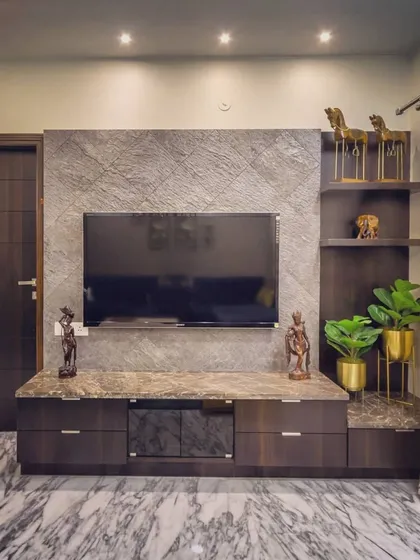 This custom TV unit combines a textured stone veneer backdrop with a polished Italian marble countertop. The dark wood drawers and open shelves provide ample storage and display space, while brass planters add a touch of metallic warmth.