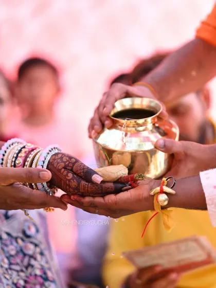 The bride's hands during a wedding ceremony, showcasing the rich, dark color of her henna.
