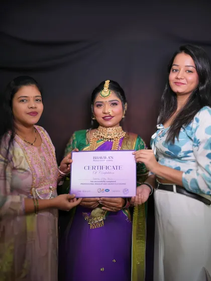 The student receiving her certificate next to her model, who is showcasing the completed Maharashtrian bridal look.