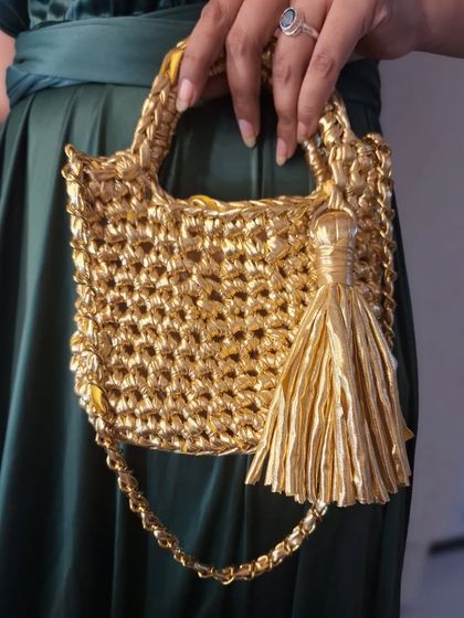 A close-up view of the 'Golden Girl' crochet bag, showing the texture of the crochet stitches and the shiny tassel. I pay close attention to every detail to make sure each bag is special.