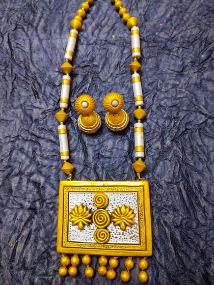 An elegant long terracotta necklace with a rectangular pendant featuring a 3D lotus motif. The dual-tone gold and silver finish makes it a very sophisticated piece.