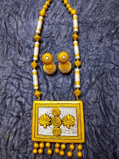 An elegant long terracotta necklace with a rectangular pendant featuring a 3D lotus motif. The dual-tone gold and silver finish makes it a very sophisticated piece.