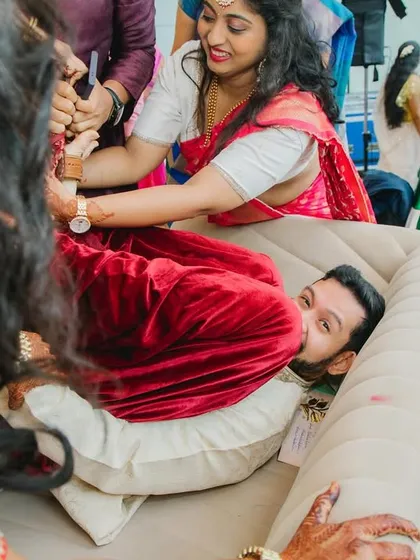 A close-up of the playful struggle during the Joota Chupai. The groom's expression is priceless as he tries to protect his shoes from his new family.