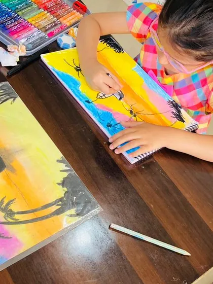 This is what pure focus looks like. Here, one of my young artists is using oil pastels to create a vibrant beach sunset. I love seeing them get lost in their work, carefully blending colors to bring their vision to life.