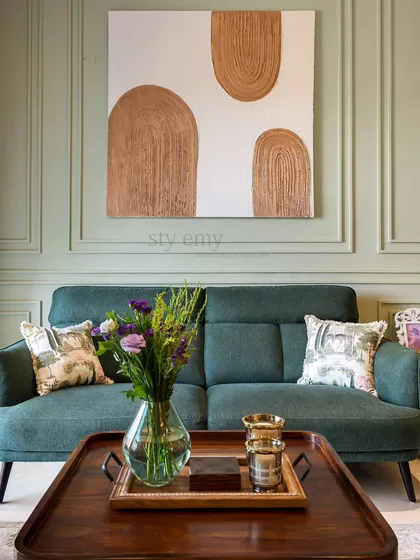 A cozy living room scene with a deep green sofa and a wooden coffee table. The textured abstract art on the wall adds a modern, artistic touch to the comfortable and stylish space.