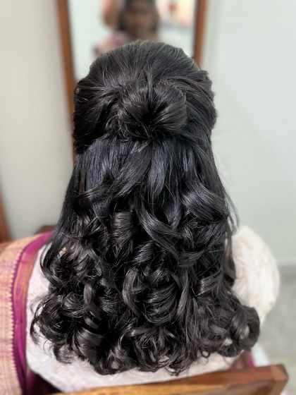 A beautiful half-up hairstyle with a knotted bun and soft curls. This is a versatile look that works for many different events.