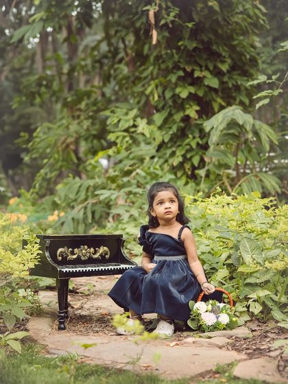 Using props like this miniature piano adds a unique and charming element to this outdoor portrait session in the park.