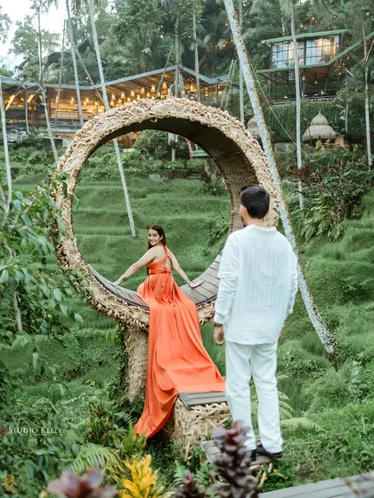 A dreamy, romantic shot from a pre-wedding session in Bali. The famous Bali swing, surrounded by lush greenery, creates a magical setting, and the flowing gown adds a touch of drama and elegance.