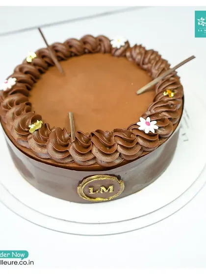 A three-quarter view of the Chocolate Truffle Cake, emphasizing its rich, glossy finish and elegant decorations.