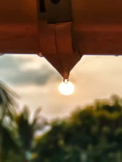 A perfect moment of perspective. I captured the rising sun inside a single droplet of water hanging from a roof, making it look like a tiny, glowing light bulb.