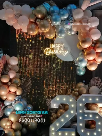A glamorous birthday backdrop for a 26th birthday, featuring a gold sequin wall, an arch of metallic balloons, and large marquee numbers.
