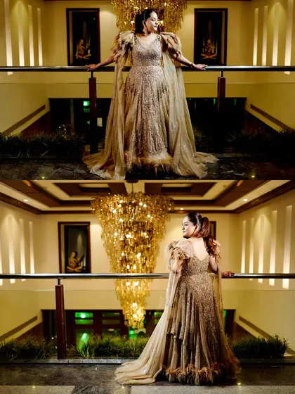 A solo portrait of the bride at her Sangeet, looking stunning in her feathered gown under a grand chandelier.