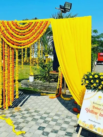 A simple and bright entrance for a Haldi function, made with marigold garlands and a personalized "Welcome to Yellow Land" sign.