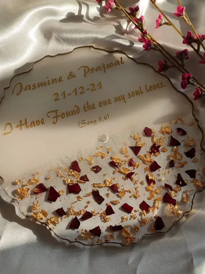 Celebrate your engagement with a personalized keepsake tray. This piece was made to commemorate a couple's special day, featuring their names, the date, and a meaningful quote. The design is finished with preserved rose petals and gold flakes on a soft white base.