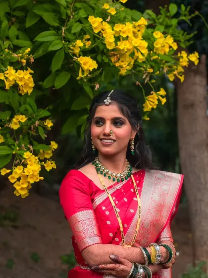 This bride's red reception saree stands out beautifully against the natural yellow flowers. Her makeup is kept radiant and fresh, with a focus on glowing skin and defined eyes.