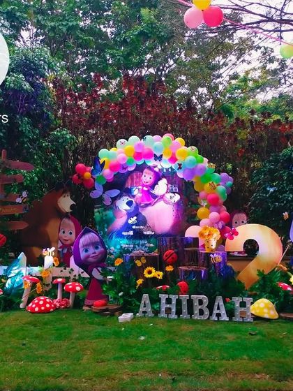 A wide view of the Masha and the Bear setup in a lush garden. The arrangement includes Masha, the Bear, the penguin, and the panda, creating a full character scene.