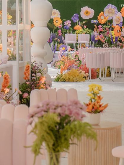 A view from the guest seats, looking towards the vibrant floral stage, framed by modern white structures.