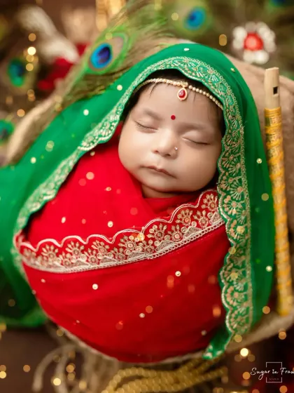 A peaceful portrait of baby Radha, swaddled in red and green with a tiny flute by her side.