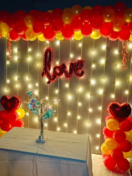 I created this simple yet charming backdrop for a celebration of love. A curtain of fairy lights is framed by red and yellow balloon columns, with a "love" foil balloon at the center.