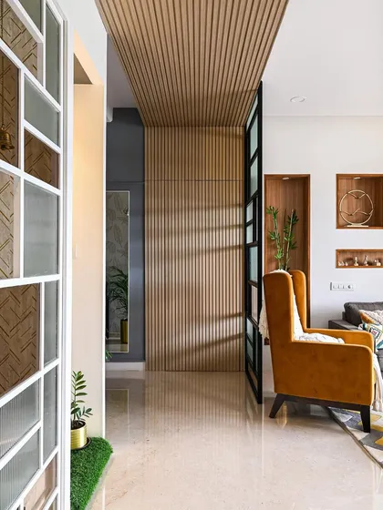 This image shows a clever hidden shoe storage solution. The fluted wooden panel wall in the entryway looks purely decorative, but a section of it is actually a concealed door.
