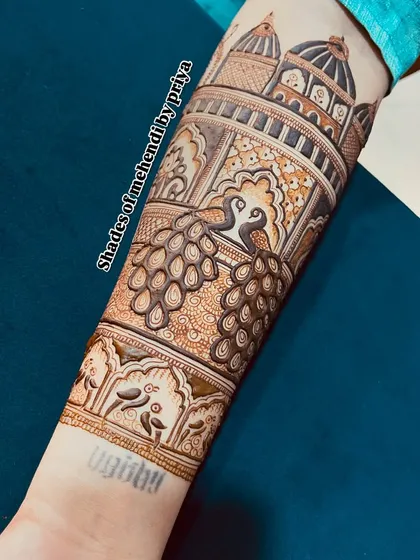 A close-up of an arm design for an engagement, featuring majestic peacocks and palace architecture.