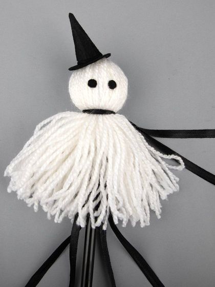 A handmade Halloween ghost wand made of white yarn.