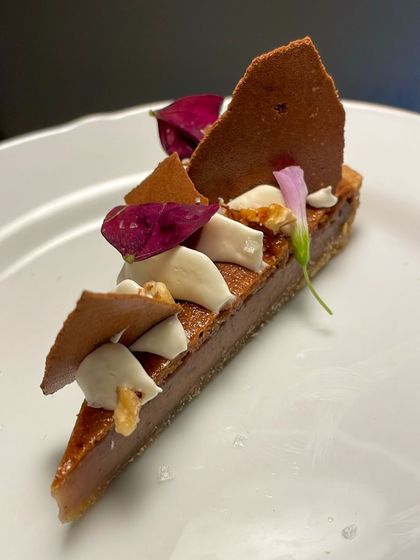 A slice of my Pecan Praline Pie. The rich, nutty filling is balanced by a creamy topping and delicate garnishes.