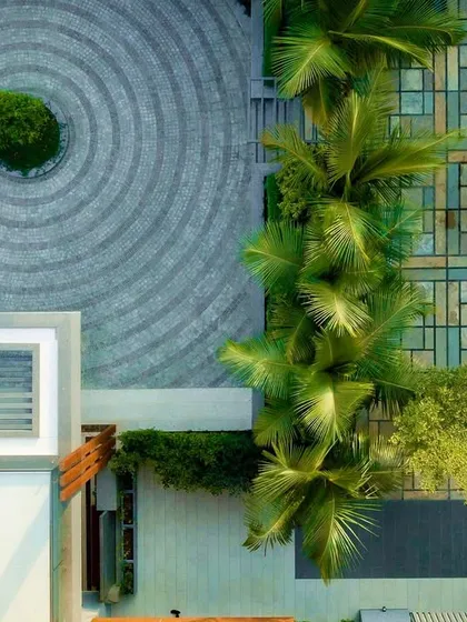 An overhead view of a villa's landscape design, where we balanced softscape with hardscape to adhere to the client's religious practices. The driveway features pavers in a radiating ripple pattern, creating a visually striking contrast with the geometric and natural textures of the garden.
